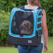 A lady carrying her dog in a blue dog traveler/carrier/stroller in her back outdoors