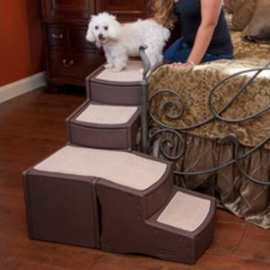 A poodle getting of Pet Gear Easy Step Bed Stair, Chocolate next to a tan bed with steel frames and a lady and wooden drawers in the background
