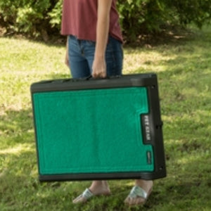 a lady hold a folded tri fold green ramp outdoors on the ground 
