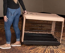 a woman wearing jeans dragging a tan colored dog crate from the floor with modern design