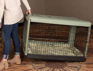 a woman dragging a large sage steel dog crate on the floor with modern design