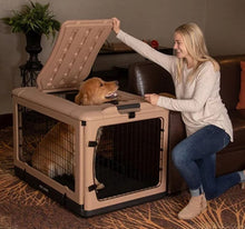 a happy woman kneeling on the floor holding the top door open for her dog inside a large tan steel dog crate next to a leather couch in a modern room with bookshelf and flower pot