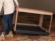 a woman dragging a large tan steel dog crate on the floor with modern design