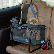a fluffy dog sticking his tongue out in a black dog carrier in the backseat of a car 