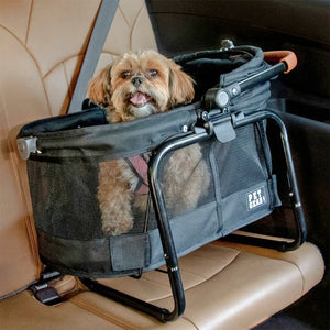 a fluffy dog sticking his tongue out in a black dog carrier in the backseat of a car