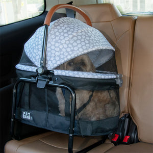 a sliver pearl designed dog carrier with a dog inside tucked at the backseat of a car