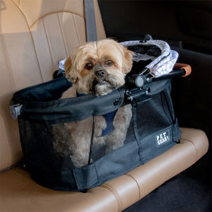 a fluffy dog inside a silver pearl designed dog carrier at the backseat of a car
