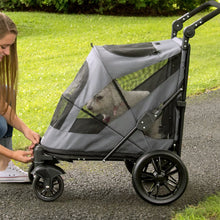 a woman tucking her dog inside a grey dog jogger in the park