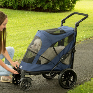 a woman tucking her dog inside a midnight blue dog stroller in the park