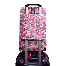 back image of a pink camo dog carrier on top of a purple luggage bag. 
