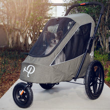 a cute dog inside a black sailboat shaped dog jogger parked in a path walk in a park with trees on the background 
