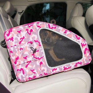 A cute dog inside of a pink camo colored pet carrier inside of a car