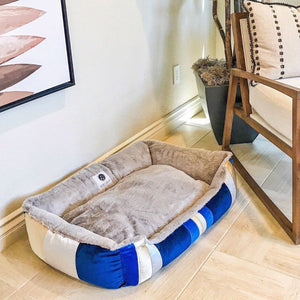 a blue dog bed next to a wooden chair a potted plant on the floor 