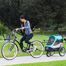 a woman riding a bicycle with her dog attached in the back of her bicycle on the park