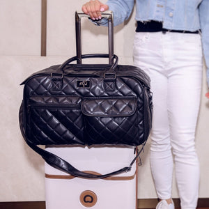 a woman holding a luggage bag and a black luxury dog carrier on top of it 