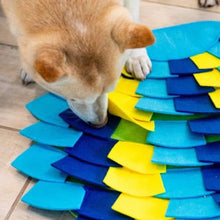 a close up image of a dog sniffing a muti colored puzzle pad for dogs