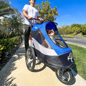 a man pushing a blue Dog Jogger Stroller with his dog inside it in the sidewalk