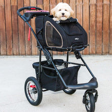 A cute dog inside of a black colored pet stroller with a black colored organizer at the bottom