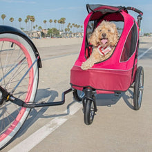 a close up image of a happy dog riding a red dog stroller on the streets
