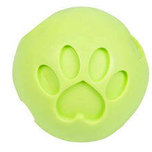a green colored dog ball treat dispenser with paw engraved to it 