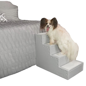a small fluffy dog standing on a grey dog stair next to a grey bed in with white background