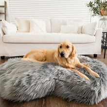 a golden retriever laying on a grey furry dog bed in front of a white couch inside a modern living room setting