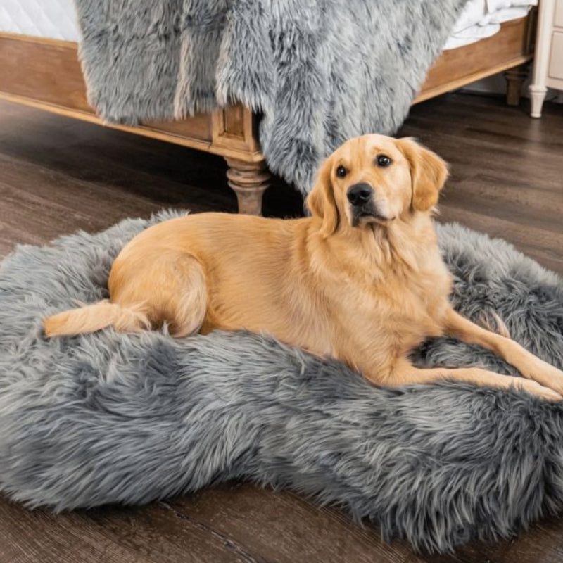 a golden retriever laying in a grey furry dog bed on the wooden floor next to wooden bed inside a modern bedroom