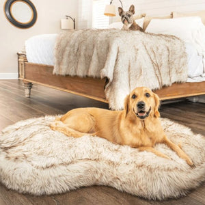 a golden retriever laying on the floor in a white fluffy dog bed and a french bulldog laying on the edge of the bed on a white fluffy dog blanket
