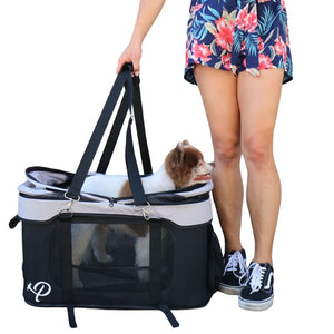a woman carrying her dog inside a black and white dog carrier 