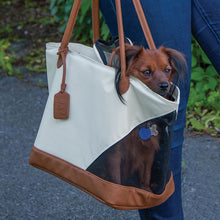 a dog sticking his head out on a Rest & Relax Tote Bag being carried by a lady walking outdoors