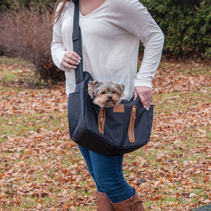 a lady in white carrying her dog outdoors on a  Sling Pet Carrier Purse, Black