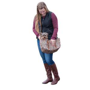 A lady wearing black vest and marron sweatshirt carrying her dog in a jaguar printed Sling Pet Carrier Purse