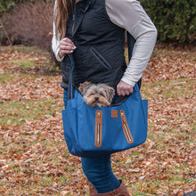 a lady wearing black vest and white sweatshirt carrying her dog outdoors on a navy blue Sling Pet Carrier Purse