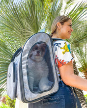 A Happy Lady wearing a Backpack Pet Carrier with a dog inside